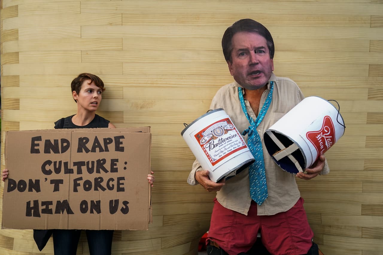 Una manifestante se puso una máscara de la cara de Kavanaugh mientras sostenía dos cubos forrados con la marca de una conocida cerveza, en alusión a las afirmaciones de algunos excompañeros del juez que han criticado sus excesos con la bebida.