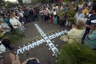 Los manifestantes protestan con una cruz formada con los retratos de las víctimas caída durante las manifestaciones que comenzaron el 12 de febrero contra el régimen de Maduro.