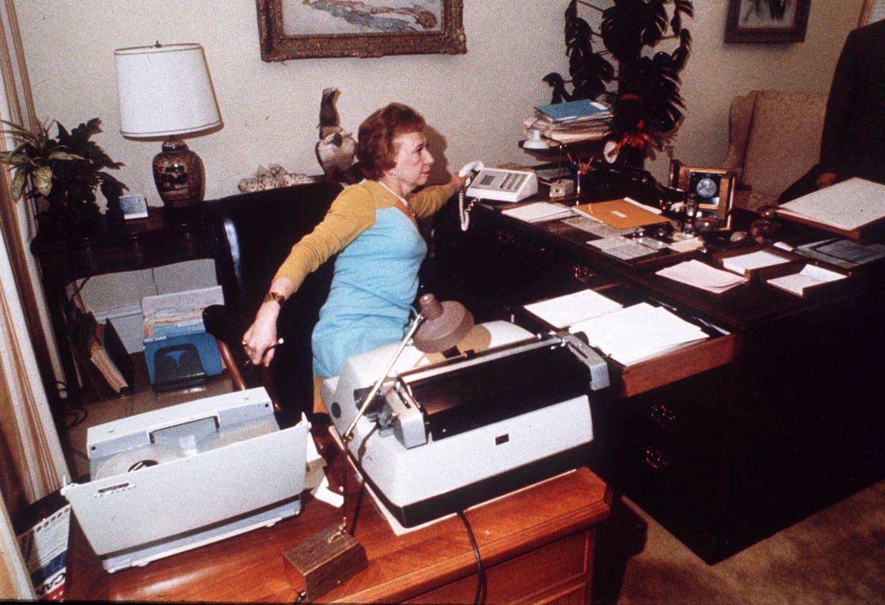 En esta foto de 1973, Rose Mary Woods, secretaria del presidente Richard Nixon en su escritorio de la Casa Blanca, demuestra el llamado "estiramiento Rose Mary" (
<i>Rose Mary Stretch,</i> en inglés) que dijo que podría haber resultado en el borrado de las grabaciones en el caso Watergate.