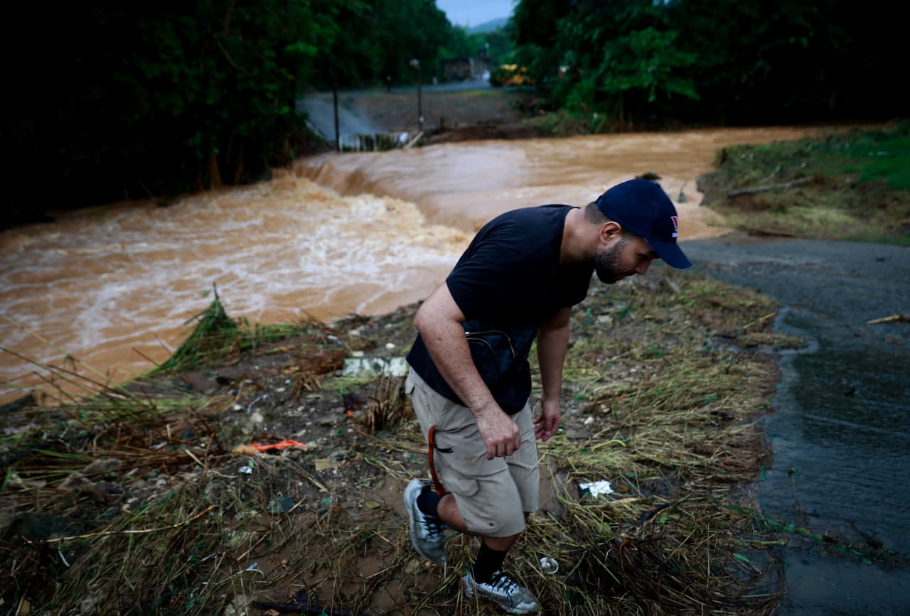Un hombre se aleja de la inundación causada por las fuertes lluvias que desbordaron el Río Turabo en Caguas.