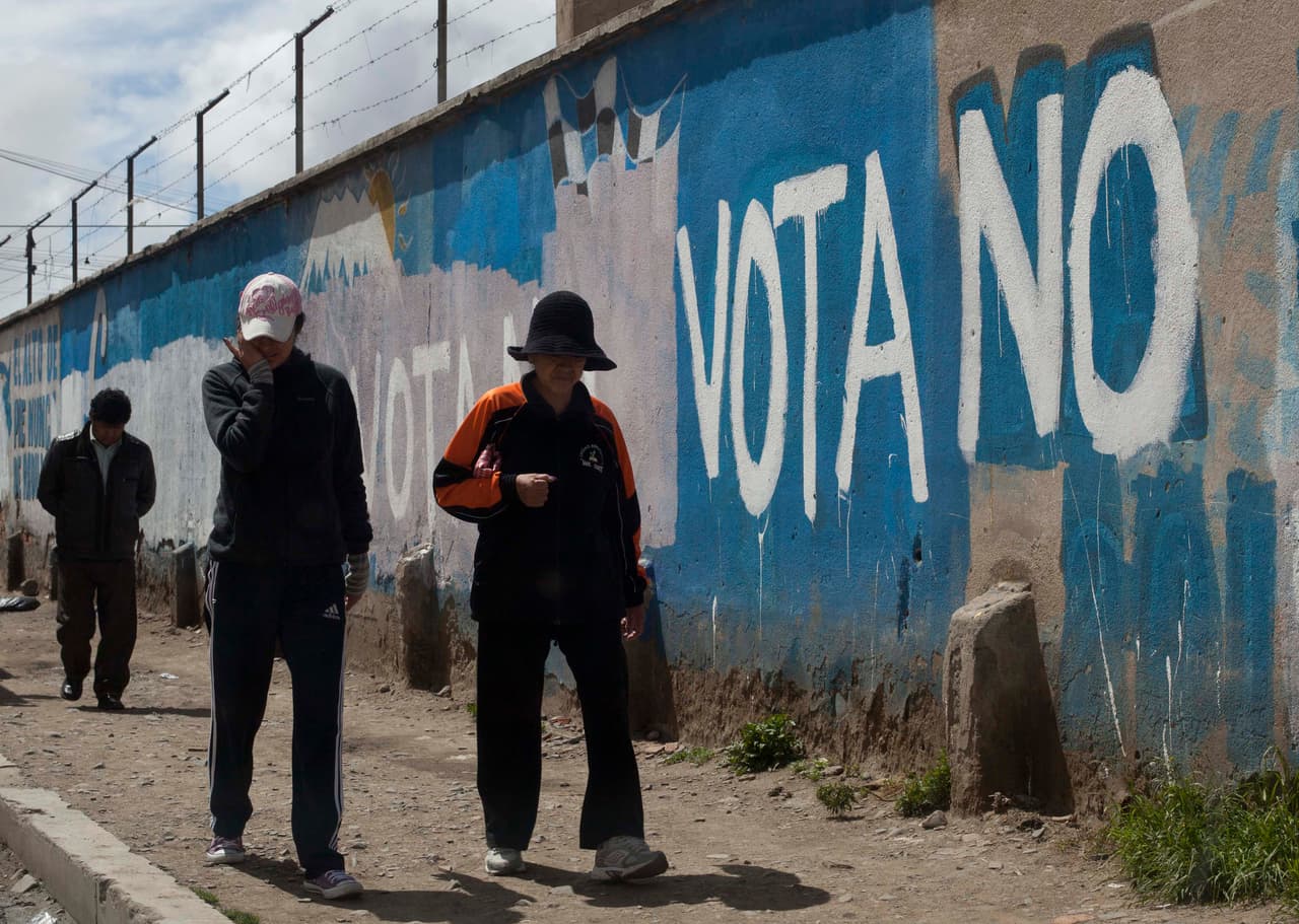 Bolivianos caminan junto a una pinta con referencia a la consulta