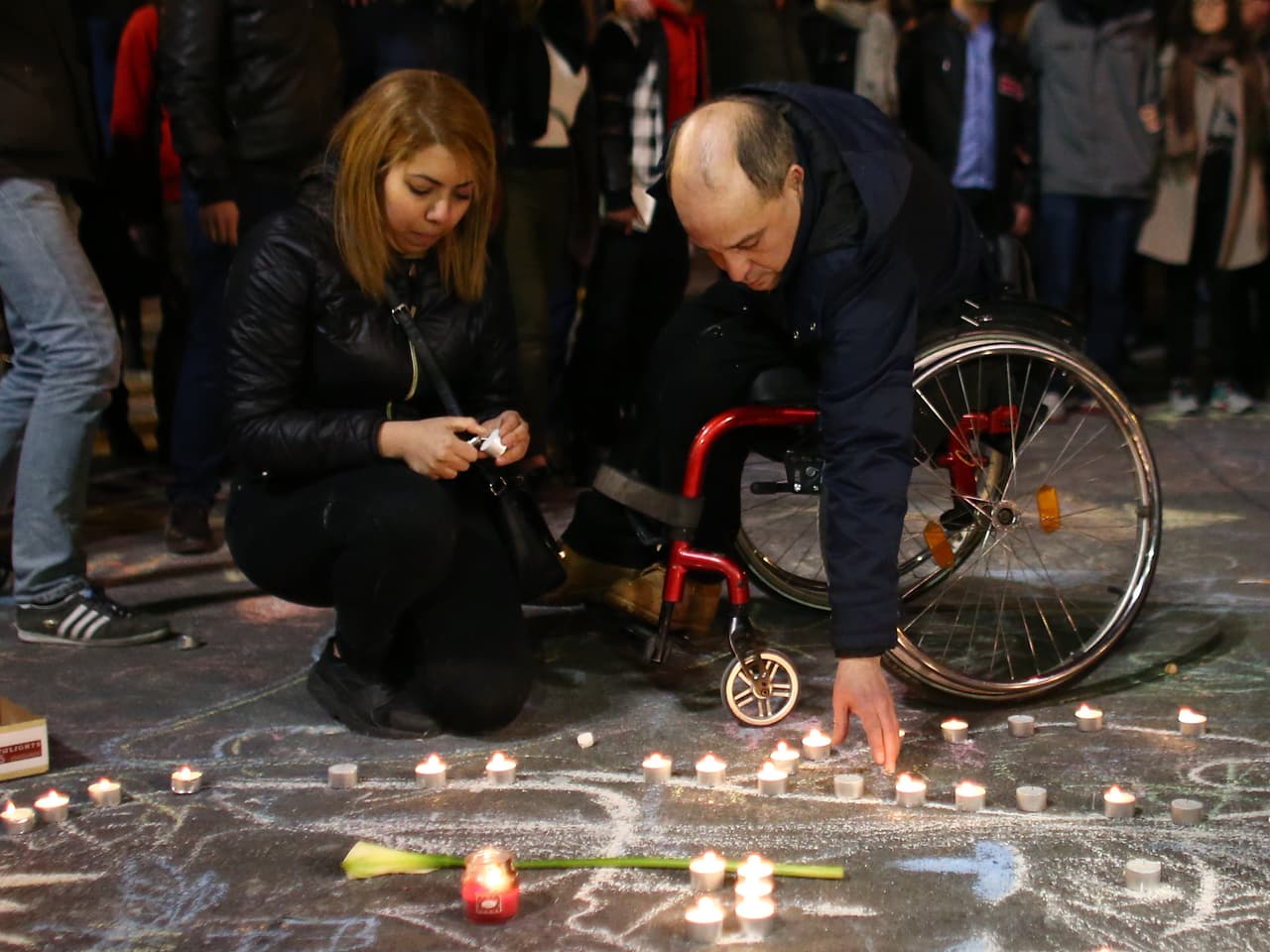 Un hombre en silla de ruedas deposita una vela encendida durante la vigilia