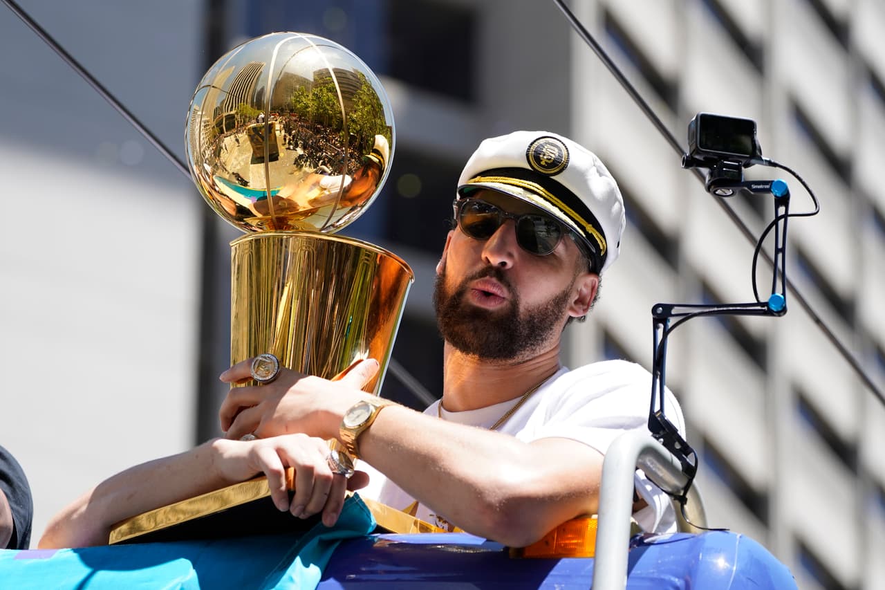 Klay Thompson usa una gorra de capitán y sostiene un trofeo mientras participa en el desfile del campeonato de la NBA de los Golden State Warriors en San Francisco, el lunes 20 de junio de 2022. (Foto AP/Eric Risberg)