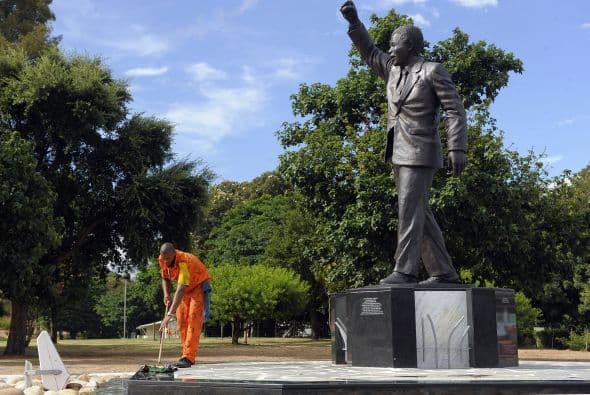 Un recluso limpia la base de una estatua de bronce que representa el ex presidente sudafricano Nelson Mandela, fuera de la prisión Groot Drakenstein en Paarl, cerca de Ciudad del Cabo.