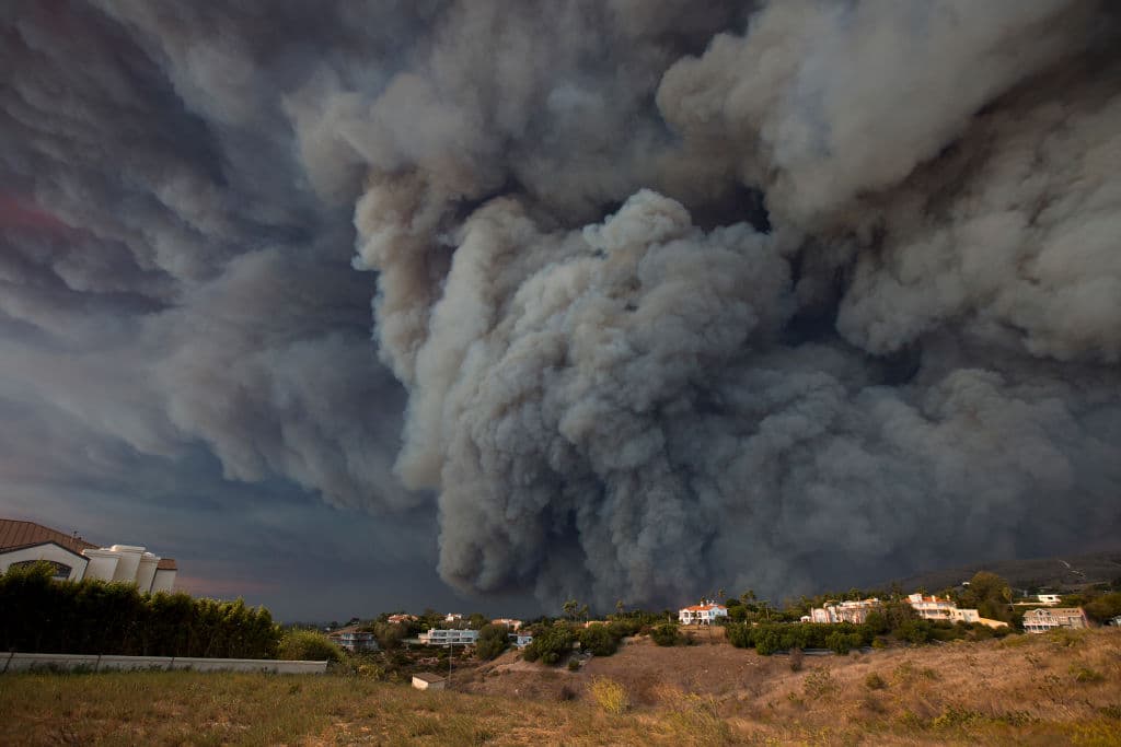 Una inmensa columna de humo potenciada por los fuertes vientos sobre las montañas de Malibu, California. Unas 75,000 viviendas han sido evacuadas en los condados de Los Ángeles y Ventura debido a dos incendios en la región.