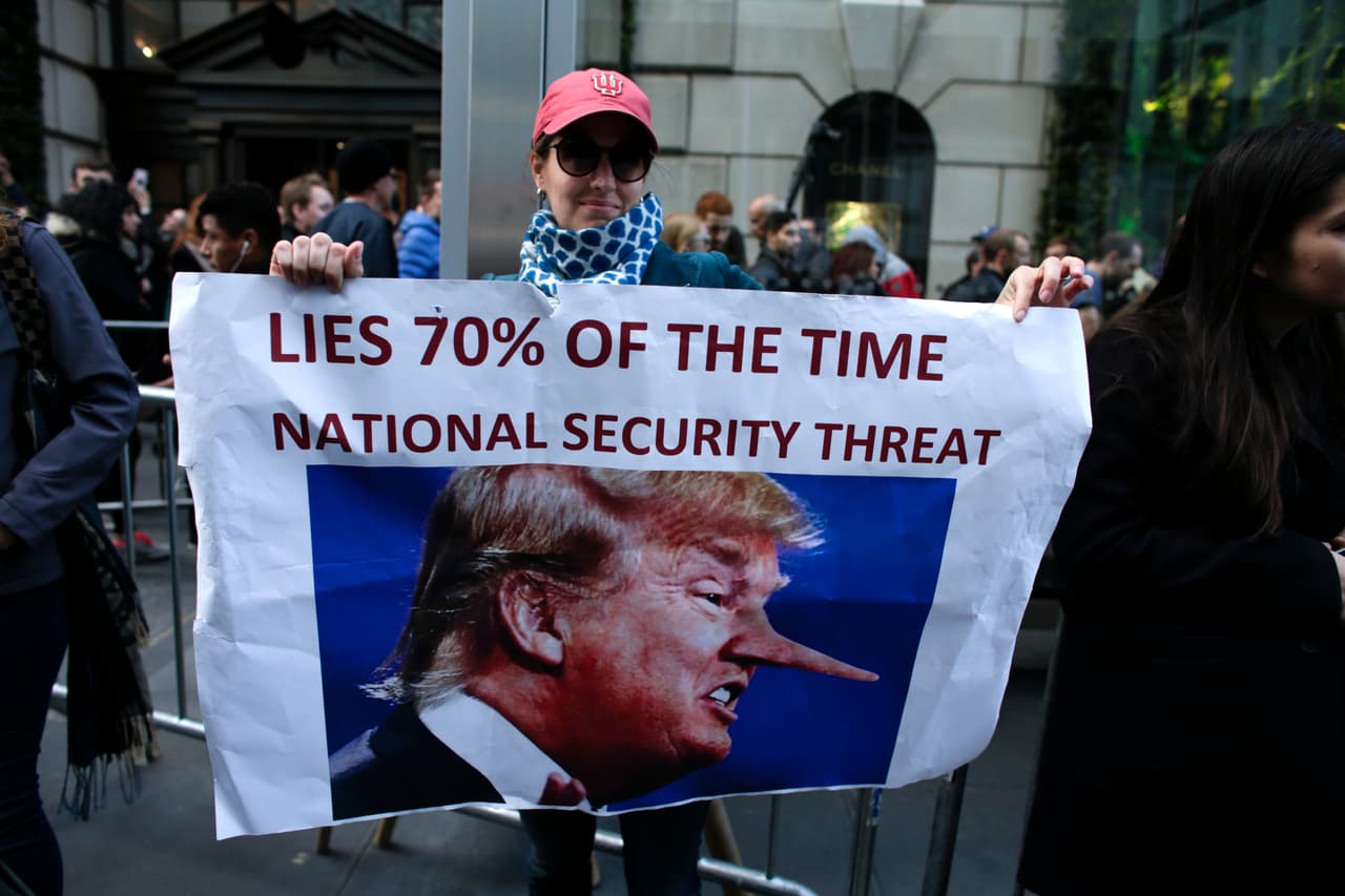 "Miente 70% del tiempo. Es una amenaza a la seguridad nacional", dice sobre Donald Trump la pancarta de esta manifestante.
