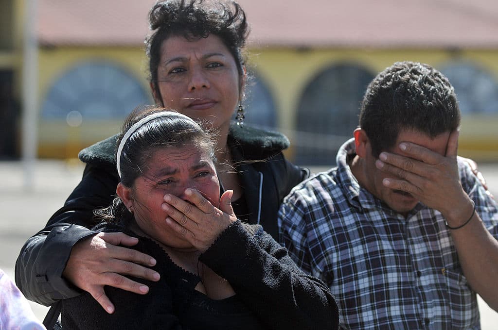 Familiares de ocho migrantes guatemaltecos asesinados en una masacre en agosto de 2010 en Tamaulipas, México, lloran mientras descargan sus ataúdes de un avión en una base de la Fuerza Aérea en la Ciudad de Guatemala, el 5 de noviembre de 2010. A