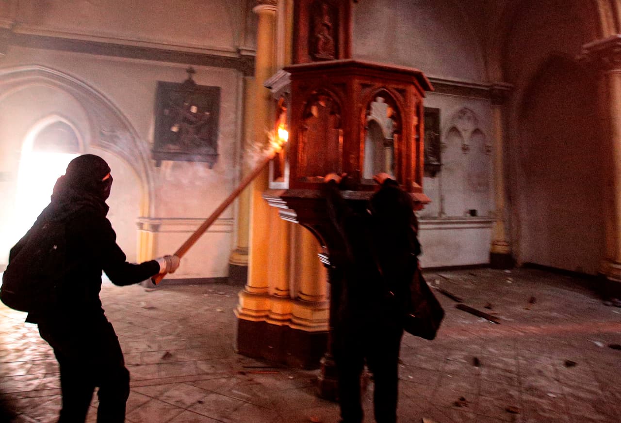 Los encapuchados dentro de la iglesia San Francisco de Borja, el otro templo destrozado en la manifestación. Autoridades chilenas calificaron los ataques a las iglesias como “una expresión de brutalidad”.
<br>