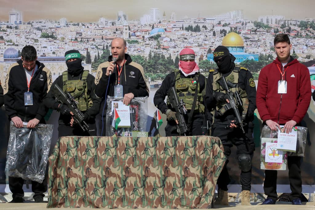 Rehenes de izquierda a derecha: el israelí-estadounidense Sagui Dekel-Chen, el rehén israelí-argentino Yair Horn y el israelí-ruso Sasha Trupanov en el escenario junto a militantes palestinos durante su entrega a un equipo de la Cruz Roja en Khan Yunis, en el sur de la Franja de Gaza, el 15 de febrero de 2025, como parte del sexto intercambio de rehenes por prisioneros.