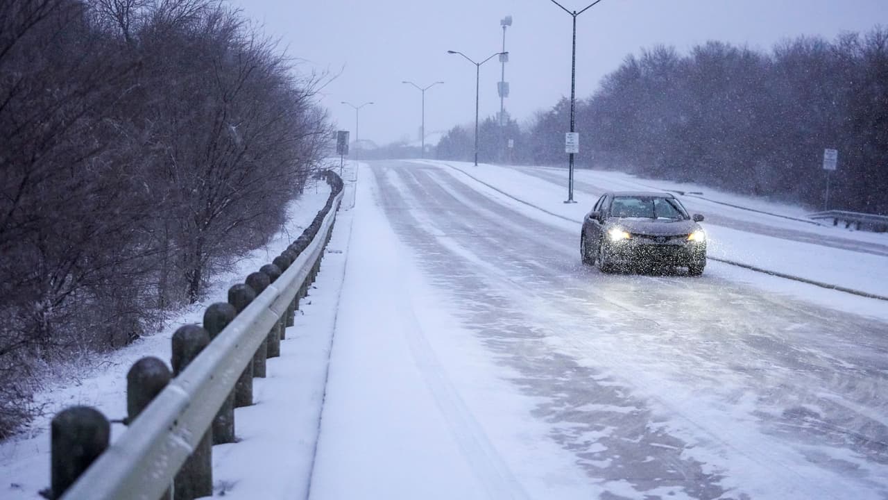 La nieve cubre una carretera mientras un vehículo circula, el lunes 15 de enero de 2024, en Grand Prairie, Texas.