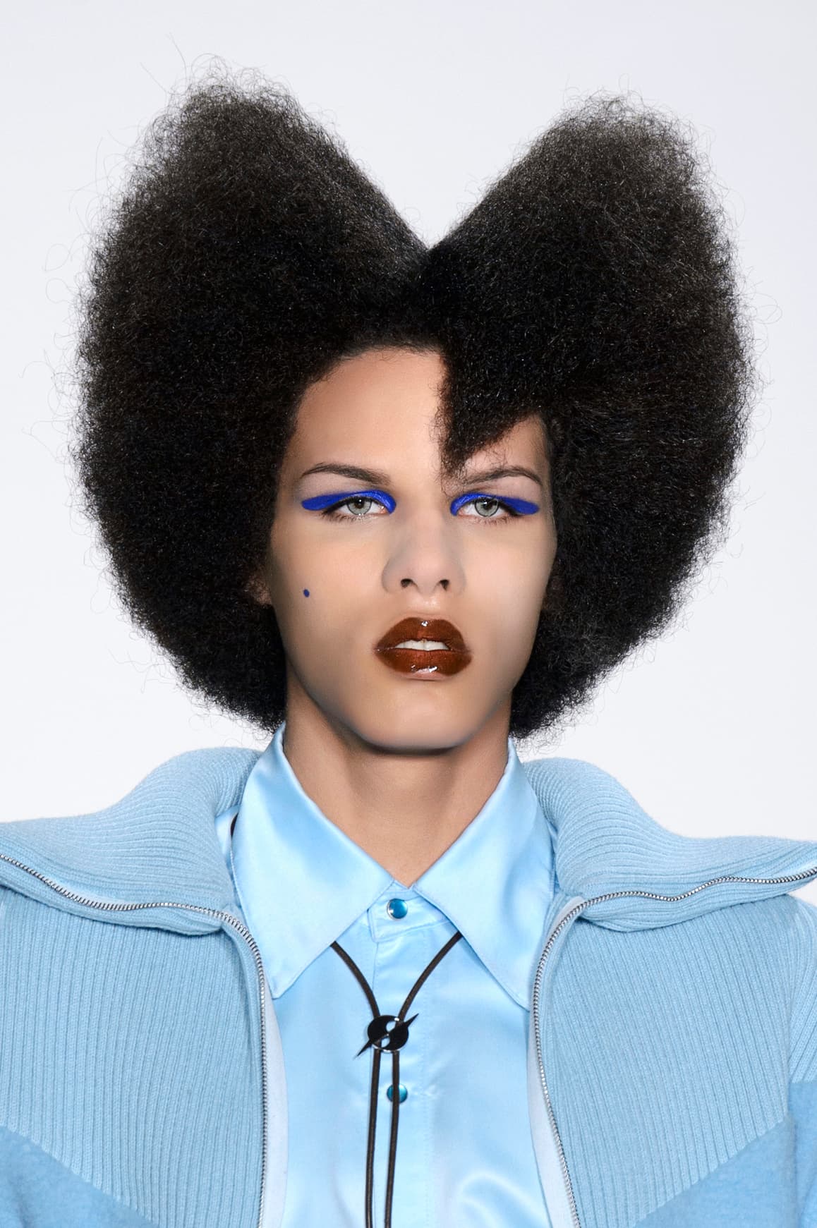 Aquí otra propuesta con el trazo gráfico como protagonista. Recuerda que este tipo de maquillaje lo puedes hacer en cualquier color, de modo que combine con el resto de tu 
<i>look</i>. Por su parte el peinado remite al villano 
<a href="http://www.imdb.com/character/ch0007759/">Jacobim Mugatu</a> de la película Zoolander. Si quieres imitarlo, lo mejor es que uses una peluca. 
<br>