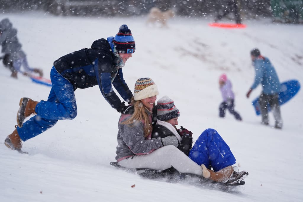 Henry Larkin, desde la izquierda, empuja a su madre Heide y a su hermana Bridget por una colina cubierta de nieve en Charlotte, Carolina del Norte, el sábado 31 de enero de 2026.
