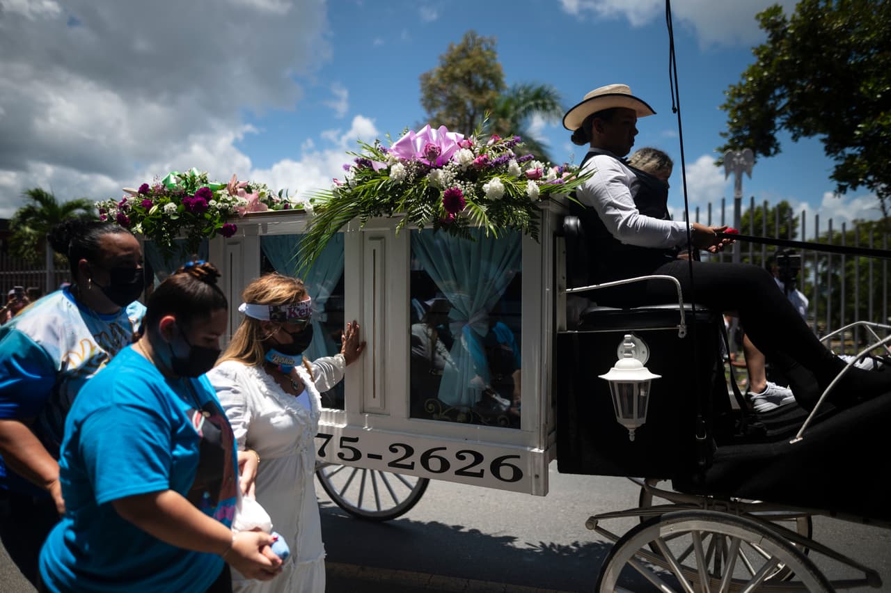 Keila Ortiz, vestida de blanco, camina junto al carruaje tirado por caballos que transporta el ataúd que contiene los restos de su hija Keishla Rodríguez.