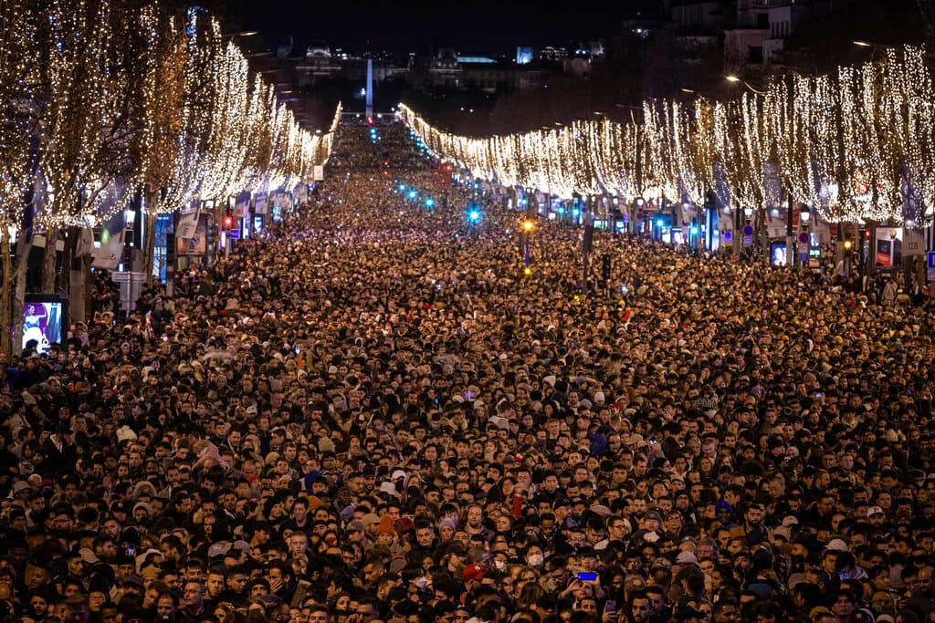 El público disfruta de un espectáculo de luz y sonido proyectado en el Arco del Triunfo mientras celebran el Año Nuevo en los Campos Elíseos, en París, Francia.