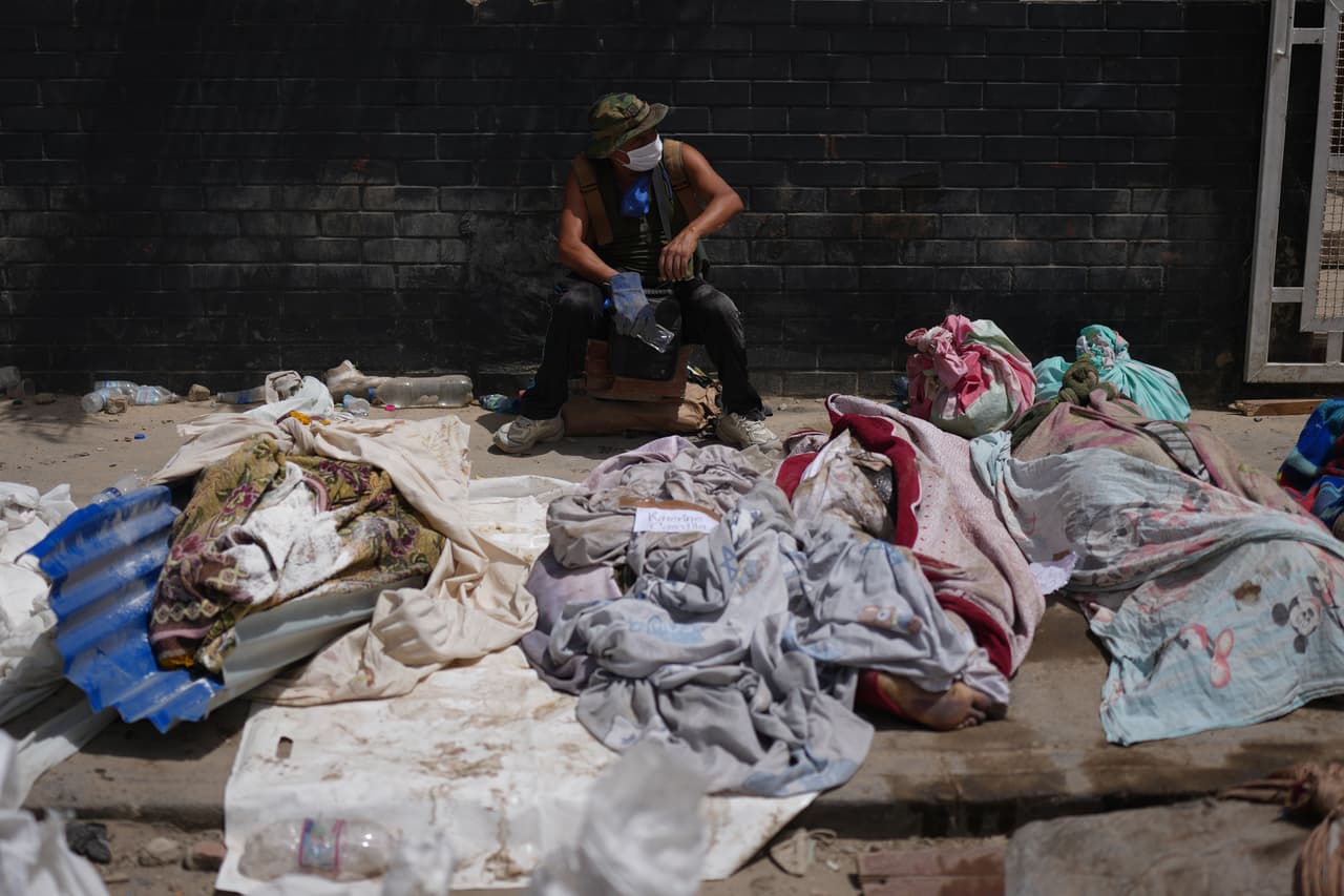 Un hombre se sienta junto a cuerpos cubiertos durante las labores de rescate tres días después de que los terremotos azotaran La Guaira, Venezuela, el sábado 27 de junio de 2026.