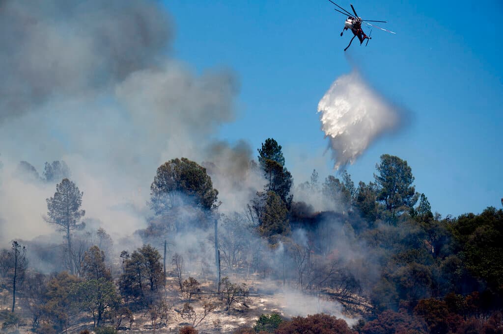 Un helicóptero rocía agua sobre el sector incendiado. Numerosas carreteras fueron cerradas, incluyendo un tramo de la Ruta Estatal 140 que es una de las principales rutas hacia Yosemite.