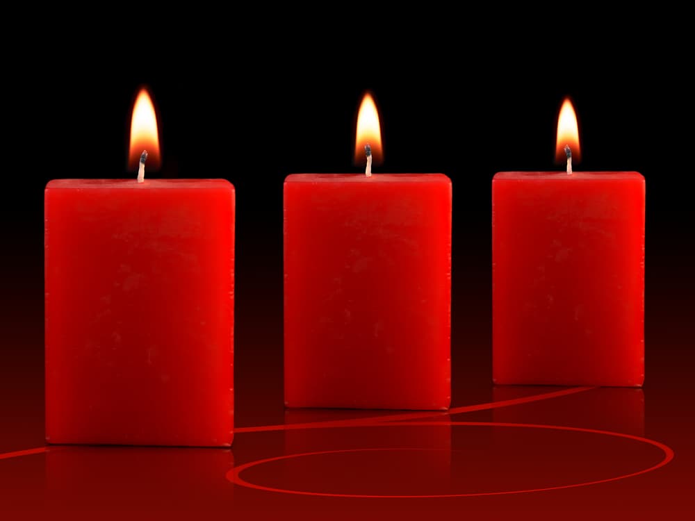 Coloca las tres velas rojas en forma de línea horizontal y préndelas con un fósforo.