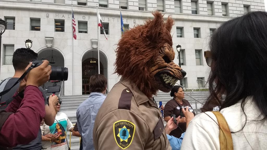 Un manifestante disfrazado de lobo con uniforme del Sheriff.