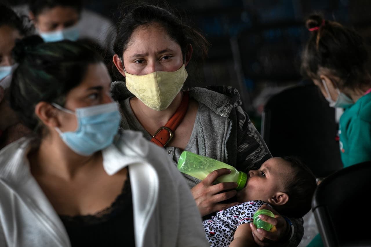 <b>Hora de comer. </b>Otra madre inmigrante sostiene a su hija mientras espera los resultados de la prueba Covid-19 el 25 de febrero de 2021.