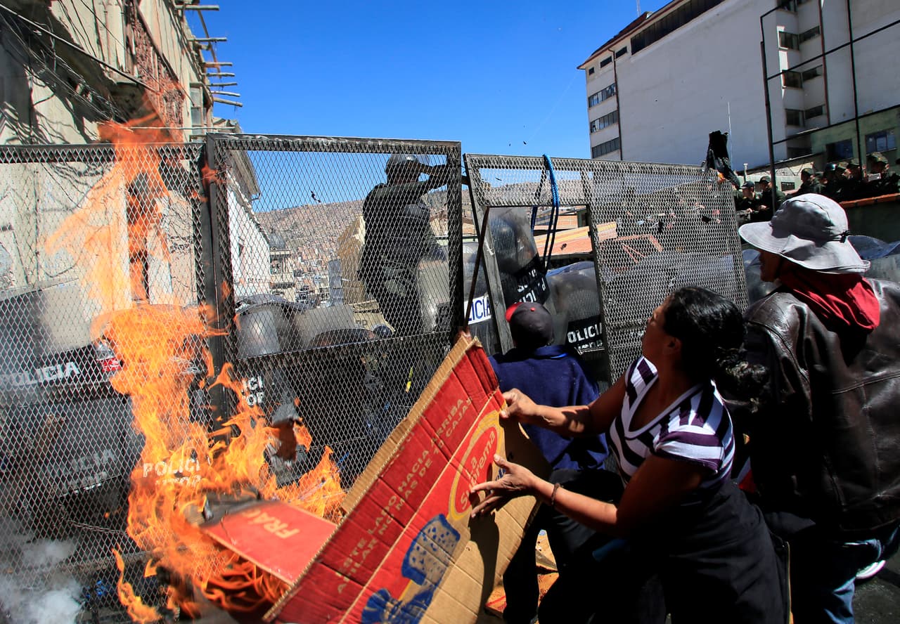 Manifestantes intentan lanzar fuego a la policia.