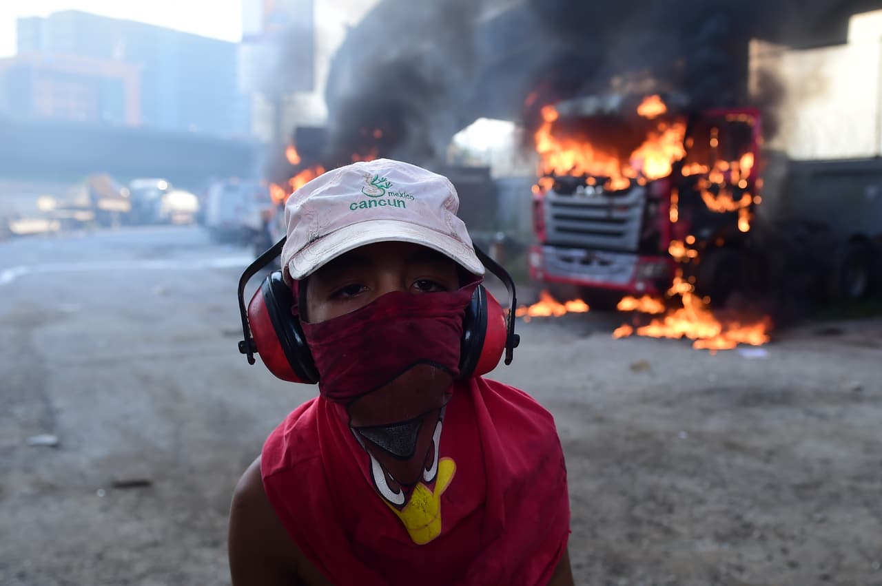 A young man participates in the protests, in front of a truck that was ignited by the protesters to block the passage in a street of Caracas.