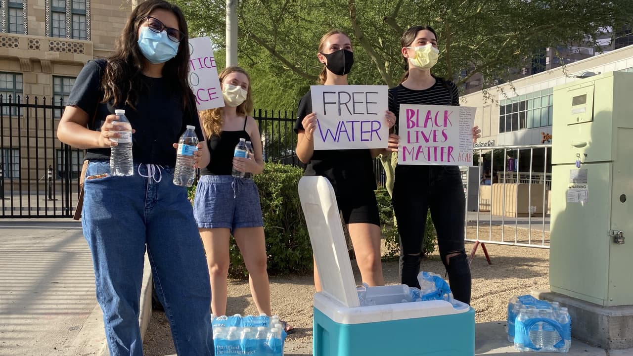 Un grupo de jovenes con una nevera portatil regalan agua a los participantes de la manifestación en su octavo día consecutivo.
