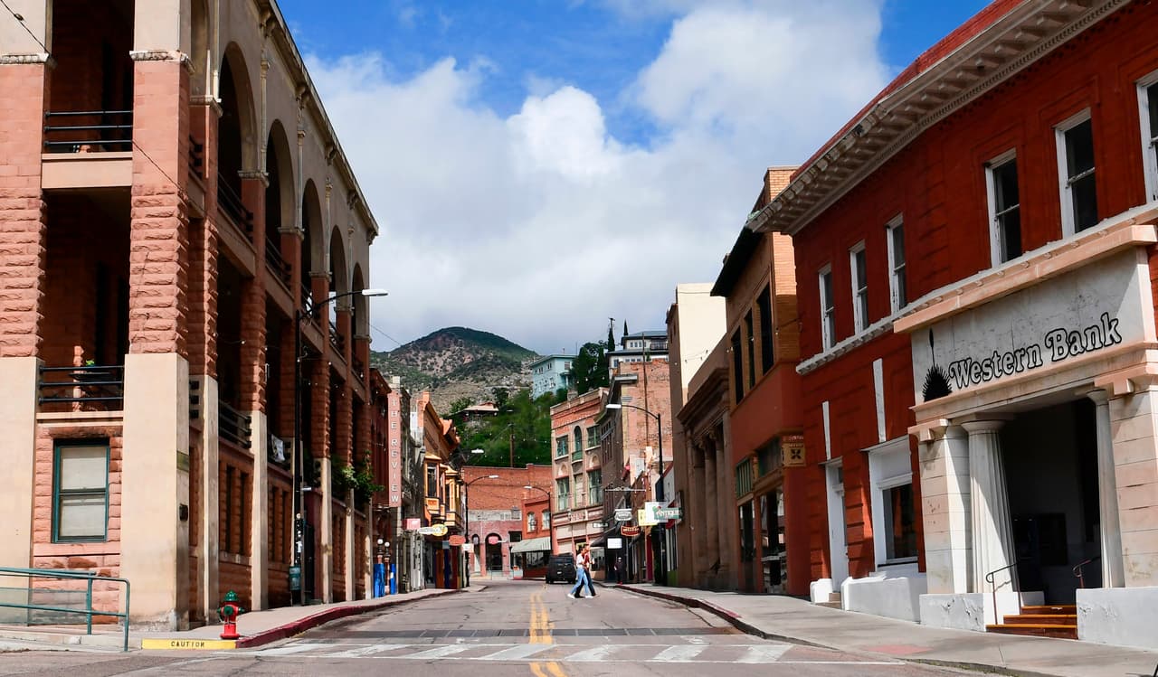Los peatones cruzan una tranquila calle principal en Bisbee, Arizona, el 24 de julio de 2020. - "Ido pero no olvidado". Así se lee en la lápida de Carl Axel Carlson, quien murió a causa de la gripe española en 1918. El tren que llevó su cuerpo desde su casa hasta Bisbee trajo consigo la mortal gripe. Más de un siglo después, este otrora floreciente pueblo minero de Arizona, ahora visitado por turistas y hogar de hippies y jubilados, está luchando por sobrevivir a una la pandemia mortal.