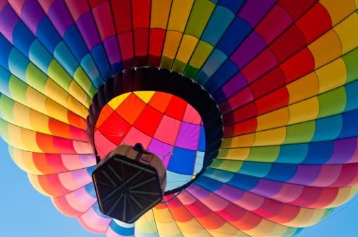 Los globos de aire caliente flotan porque el aire caliente dentro de la envoltura tiene una densidad menor que el aire más frío afuera.