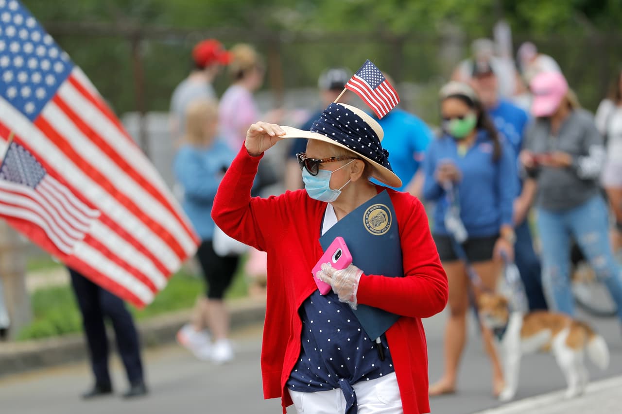 Una mujer se sostiene el sombrero mientras se reúne con personas fuera del Monumento Nacional y Santuario Histórico Fort McHenry, donde el presidente Donald Trump asiste a una ceremonia del Día de los Caídos.