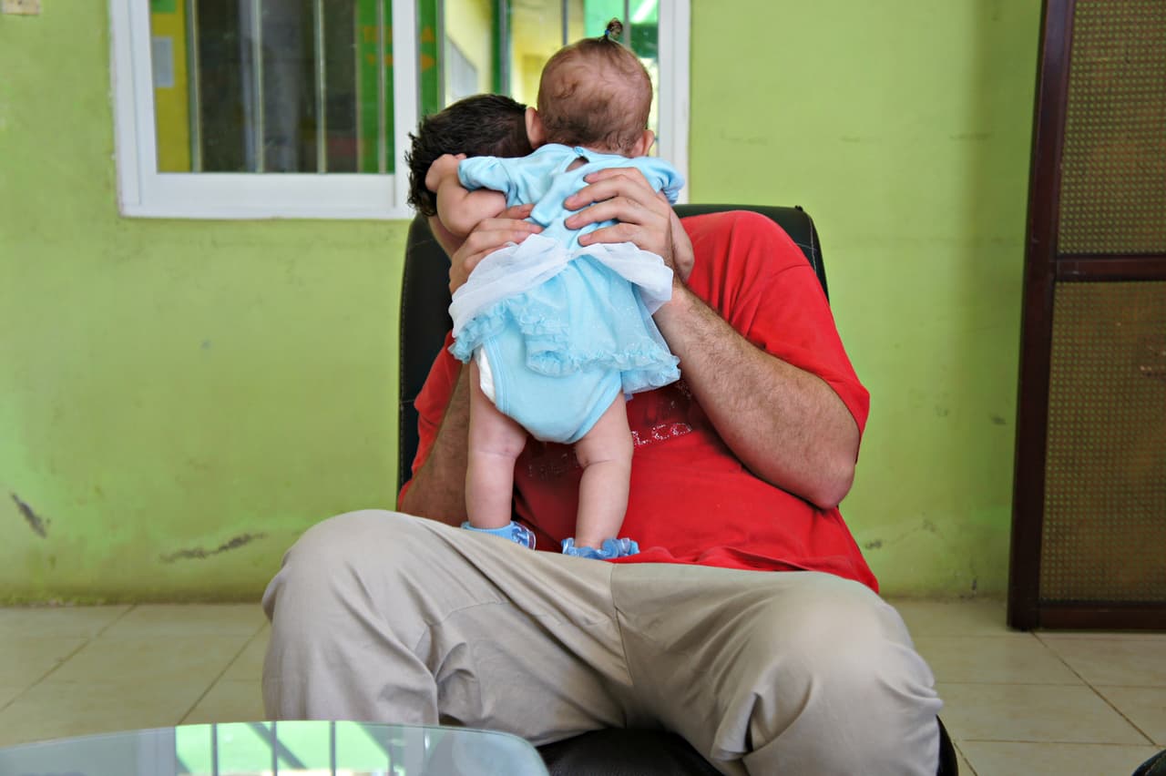 David, a 33-year-old woodworker from El Salvador, plays with his three-month-old baby in Tapachula, Mexico.