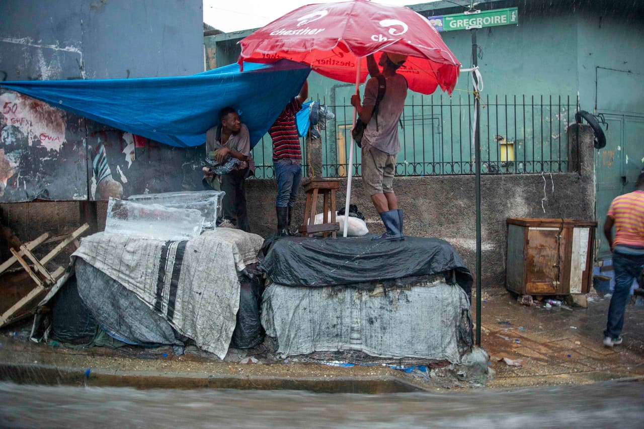 Vendedores ambulantes se protegen de las lluvias en Puerto Príncipe, Haití.
<br>
<br>Laura provocó la suspensión del servicio eléctrico y de agua en la isla La Española, se espera que en su recorrido hacia Estados Unidos pase por Cuba entre el domingo y el lunes antes de llegar al Golfo de México.