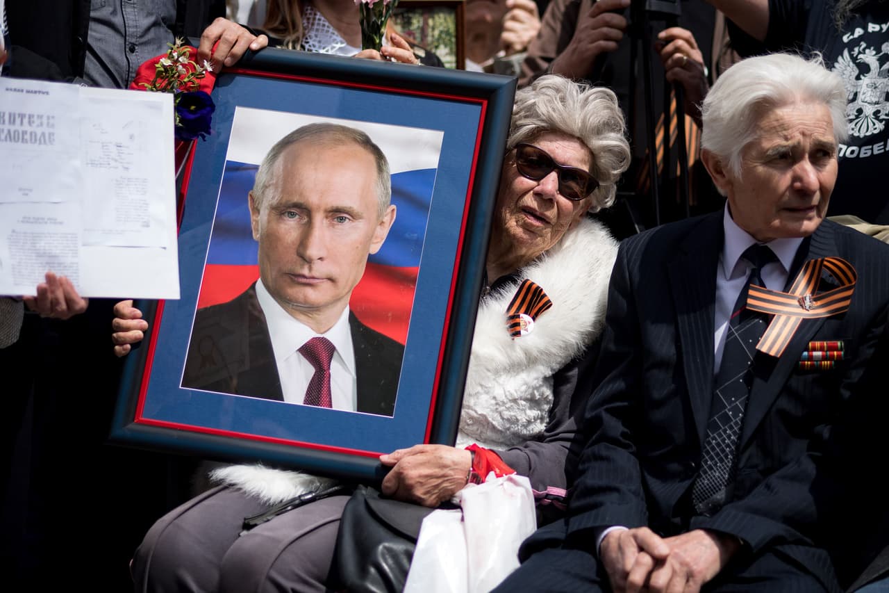 Una mujer lleva un retrato de Vladimir Putin, en la conmemoración del Día de la Victoria en Belgrado, Serbia, parte de la desaparecida Yugoslavia.