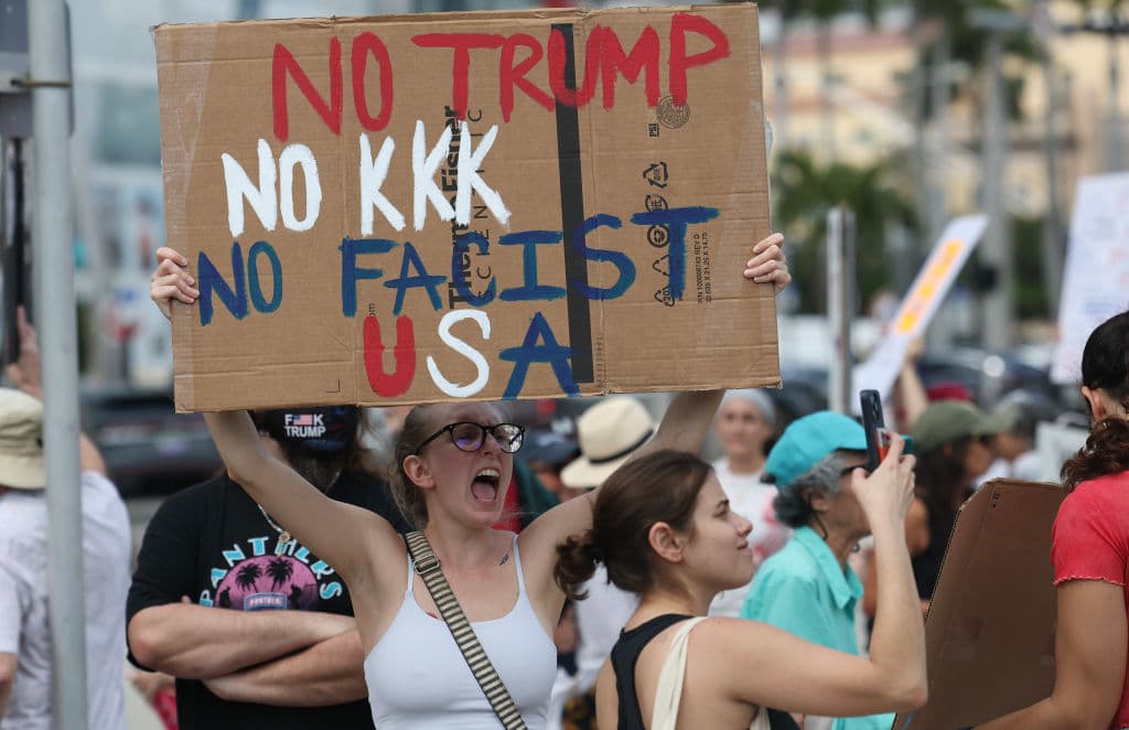 Una joven sostiene un cartel en la protesta contra Trump que se efectuó en Miami durante el Día del Presidente.
