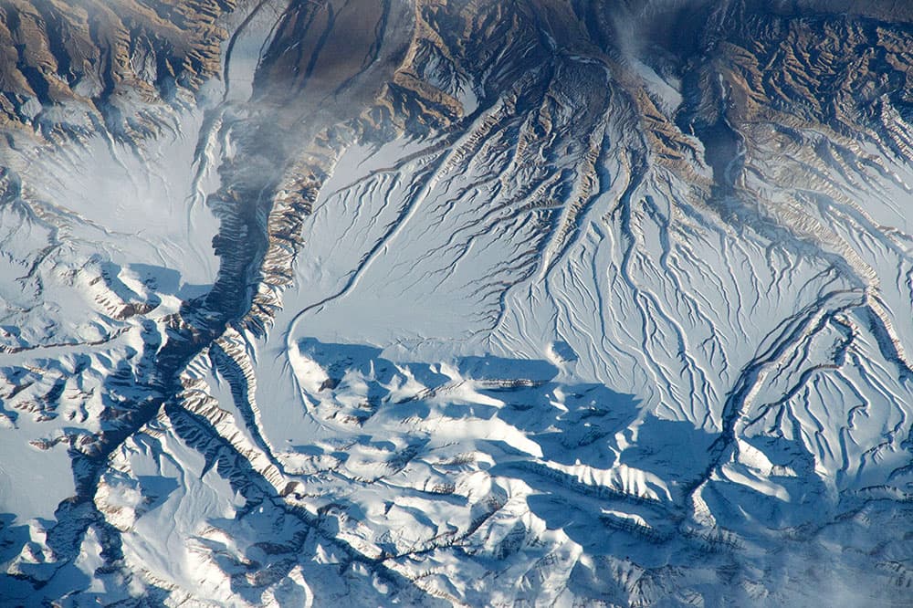 Esta imagen fue tomada cuando los astronautas sobrevolaron la cordillera del Himalaya en China, cerca de la frontera con India. La vista muestra una de las principales cadenas de montañas del Himalaya en la parte inferior de la imagen, donde los picos arrojan fuertes sombras de la noche contra la nieve.