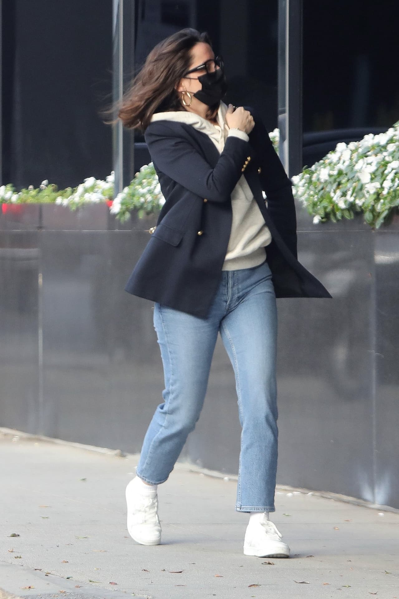 <b>Ana de Armas</b> no teme combinar una sudadera deportiva con el clásico saco negro durante una casilda casual. Aquí los pequeños detalles lo vuelven muy elegante, pues los botones dorados de la prenda combinan con los aretes, mientras que los lentes y el cubrebocas son negros.