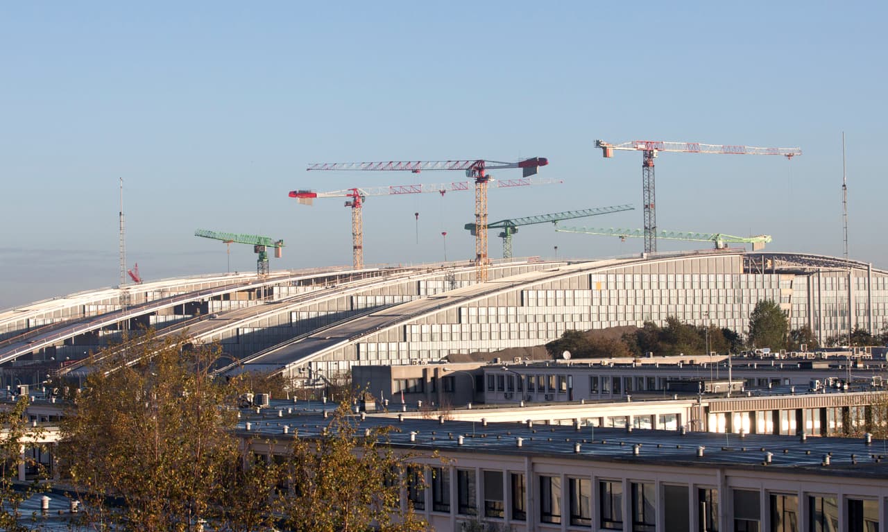 Vista de la anterior sede de la OTAN y de la nueva sede en construcción en 2013. En el sistema de financiamiento común de la organización, cada país cubre los costos de la obra según el espacio que se le será asignado en las oficinas, por la representación militar y el tamaño de las delegaciones.