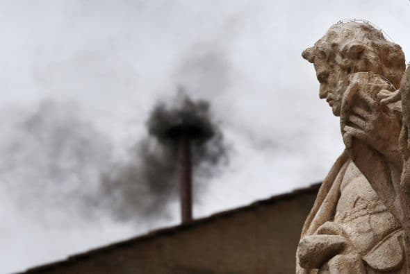 Sale humo negro de la chimenea que se encuentra en el techo de la Capilla Sixtina en el Vaticano.