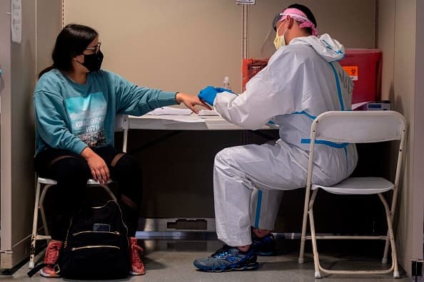 A lab technician administers a voluntary free Covid-19 rapid test to a passenger arriving at the Luis Munoz Marin Airport in San Juan, Puerto Rico on June 30, 2020. (Photo by Ricardo ARDUENGO / AFP) (Photo by RICARDO ARDUENGO/AFP via Getty Images)
