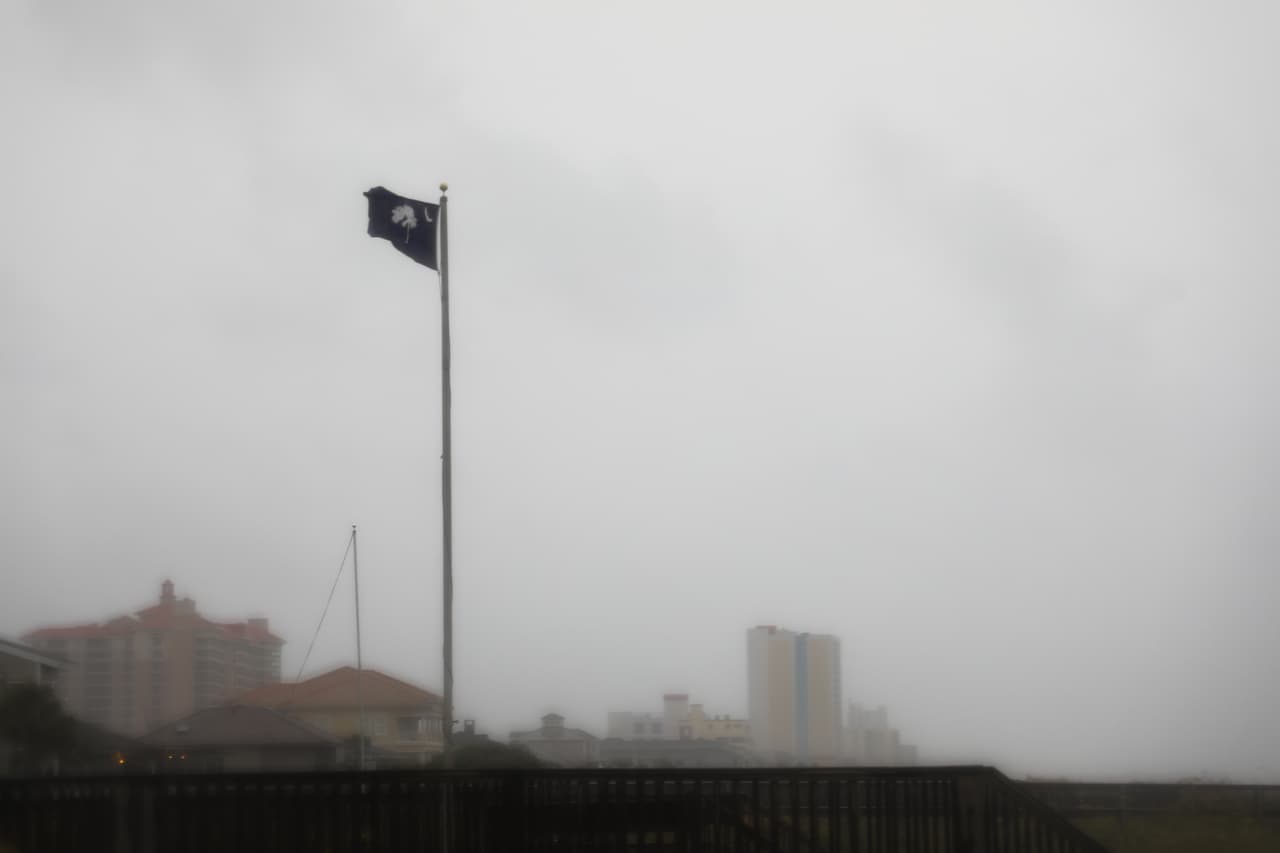 Una bandera del estado de Carolina del Sur ondea salvajemente por el fuerte el viento antes de que el huracán Isaías llegase a la costa de Carolina del Sur en North Myrtle Beach. El NHC emitió una advertencia de huracán para un área entre el río South Santee, en Carolina el Sur, y Surf City, en Carolina del Norte.