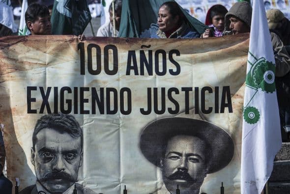 Los campesinos sostienen un cartel con los idealistas Pancho Villa y Emiliano Zapata.  