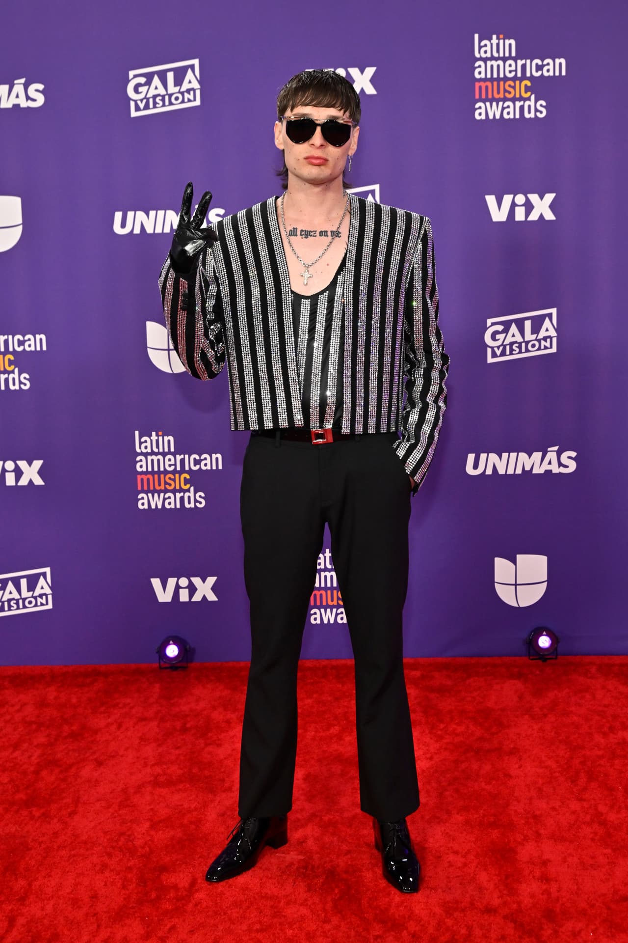 <b>Peso Pluma </b>
<br>
<br>El cantante le dio un toque de brillo y glamour a su tradicional estilo al lucir un traje de pantalones negros y una chaqueta y top de brillantes.