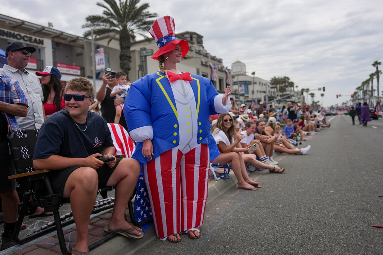 Madyson White, vestida con un disfraz inflable del Tío Sam, saluda mientras observa un desfile del Día de la Independencia en Huntington Beach, California, el sábado 4 de julio de 2026.