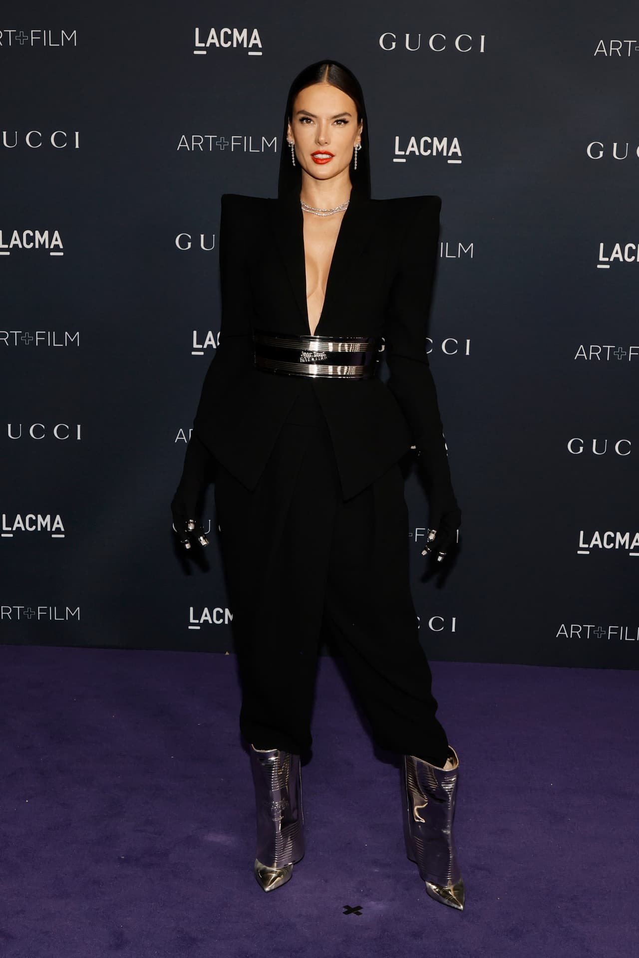 Alessandra Ambrosio lució un traje de Jean Paul Gaultier en color negro en el que resaltaban accesorios como el cinturón ancho metálico y guantes negros con ese mismo toque de metal en la punta de los dedos. La botas metálicas fueron pieza clave en su look.