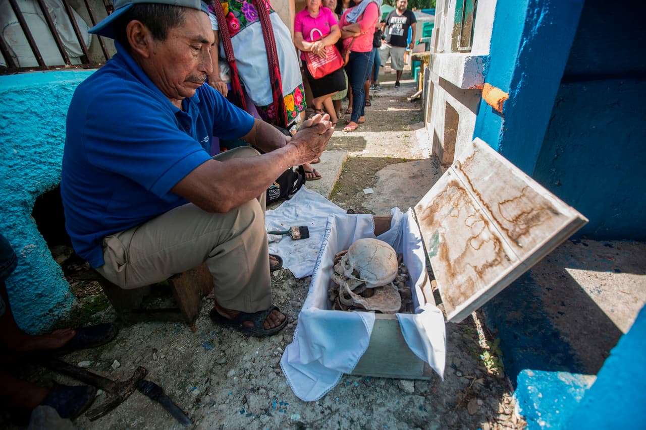 Días antes del 
<b><a href="https://www.univision.com/temas/dia-de-los-muertos">Día de Muertos</a></b>, los miembros de la comunidad se acercan al cementerio y hablan con los restos de sus seres queridos, una tradición que fusiona las costumbres indígenas con las creencias europeas. En la imagen, un hombre habla a los huesos de uno de sus familiares.