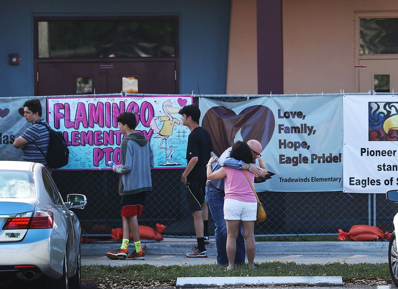 La gente se abraza frente al edificio de primer año en el que tuvo lugar el tiroteo masivo en Marjory Stoneman Douglas High School.