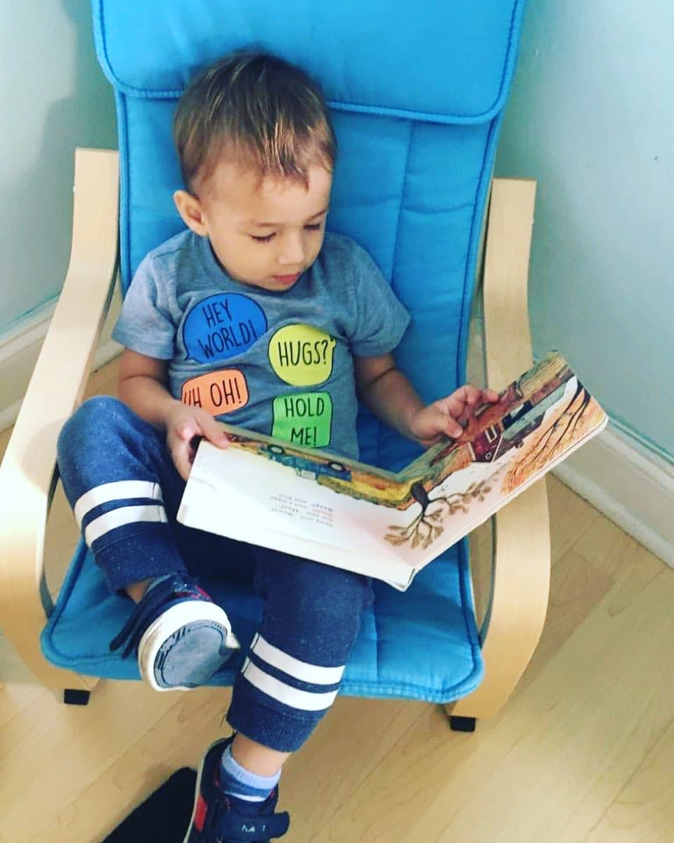 Aunque aún no sabe leer, Liam, de 2 años 6 meses, disfruta hojear sus libros favoritos en casa.