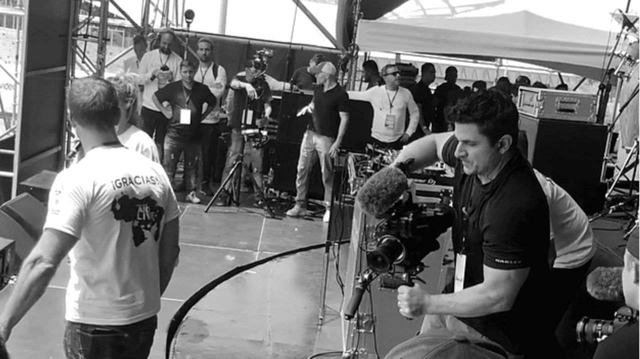 Jordan Goudreau en el escenario del 'Venezuela Aid Live' en Cúcuta, en el centro al fondo, vestido con jeans y camiseta oscura en febrero de 2019.