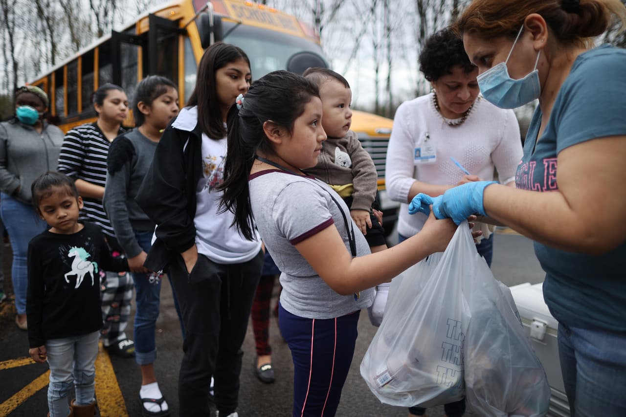<b>Ayuda para los más necesitados.</b> Docenas de familias reciben alimentos distribuidos por las escuelas públicas del condado de Montgomery, Maryland, el 20 de marzo. En EEUU millones de niños dependen de las comidas que reciben en la escuela, ahora cerradas para evitar la propagación del coronavirus.