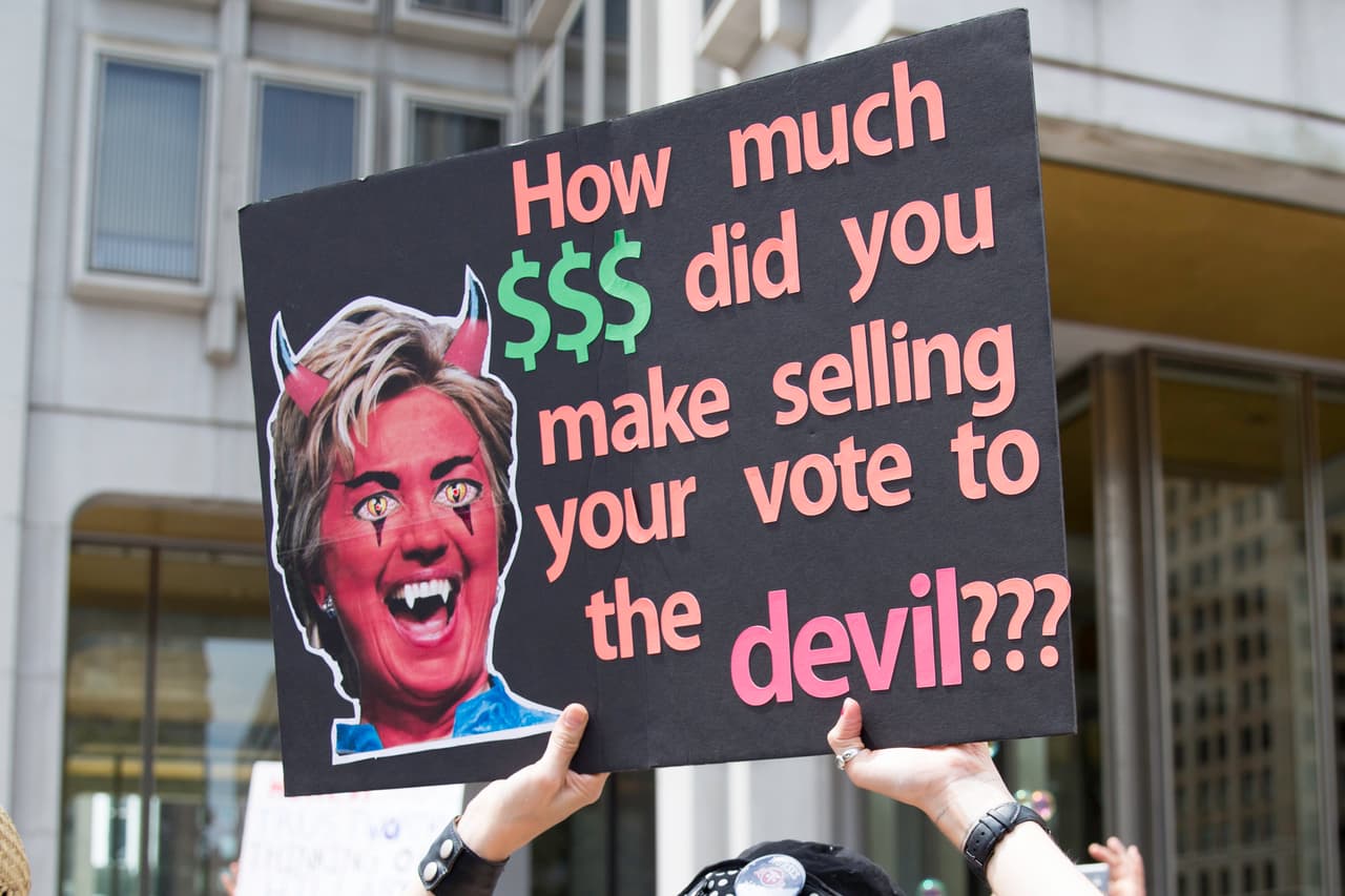 En este cartel en contra de la candidata candidata Clinton, visto en una concentración a favor de Bernie Sanders, se lee “¿Cuánto ganaste vendiendo tu voto al diablo?”.
