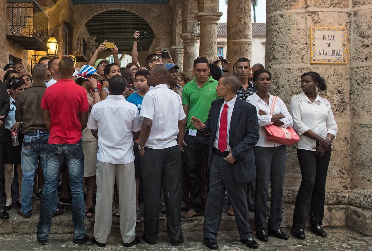 Agentes de la seguridad cubana se mantienen pendientes mientras las personas esperan la llegada de Obama.